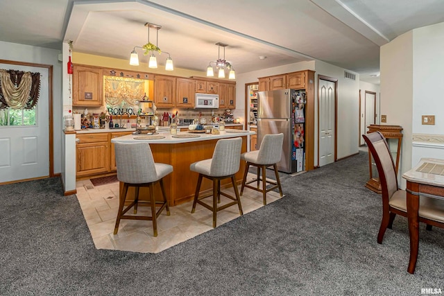 kitchen with a notable chandelier, a center island, light colored carpet, and stainless steel fridge