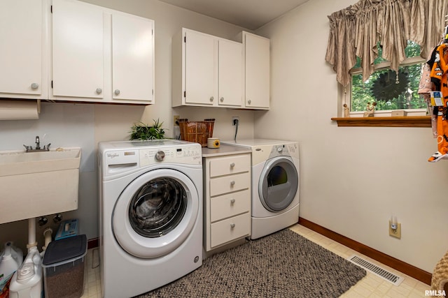 laundry area featuring sink, washing machine and clothes dryer, and cabinets