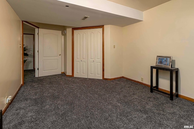 unfurnished bedroom featuring dark carpet and a closet