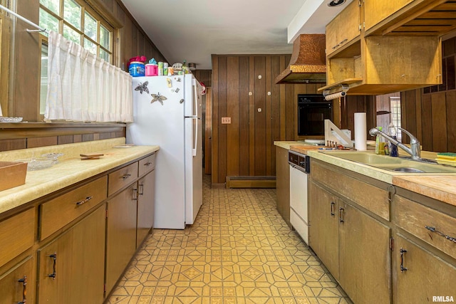 kitchen featuring white appliances, wooden walls, sink, and a baseboard radiator