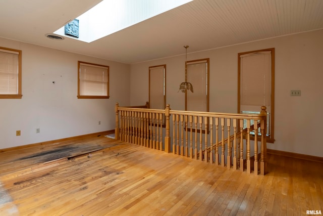 spare room with light wood-type flooring and a skylight