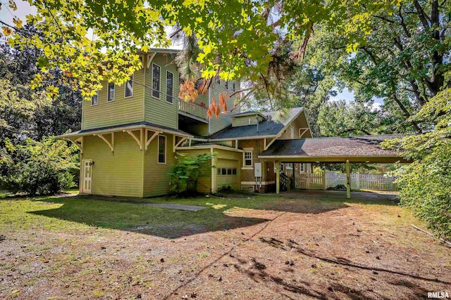 rear view of house with a lawn and a carport