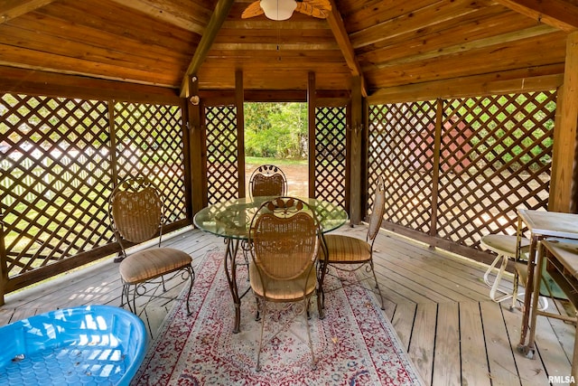 unfurnished sunroom featuring ceiling fan, lofted ceiling with beams, and wooden ceiling