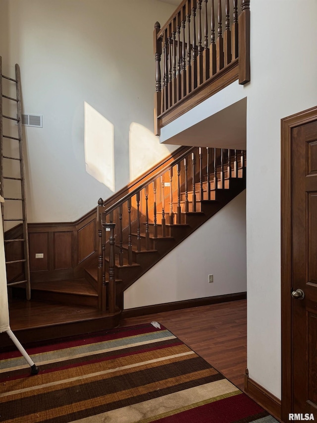 stairs with hardwood / wood-style flooring and a towering ceiling