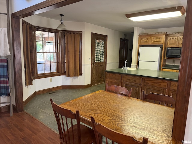 kitchen with decorative light fixtures, black microwave, sink, dark tile patterned flooring, and white refrigerator