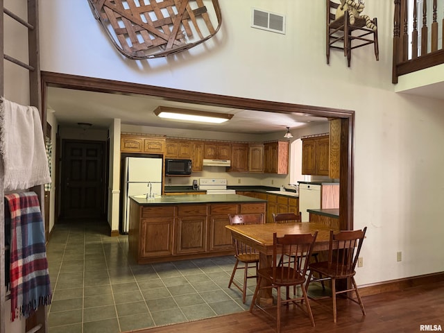 kitchen with white appliances, dark tile patterned floors, sink, and a high ceiling