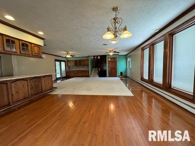 unfurnished living room with hardwood / wood-style flooring, ceiling fan with notable chandelier, crown molding, and a textured ceiling