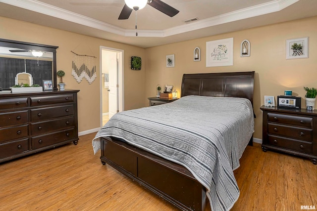 bedroom featuring ceiling fan, a tray ceiling, connected bathroom, and light hardwood / wood-style flooring