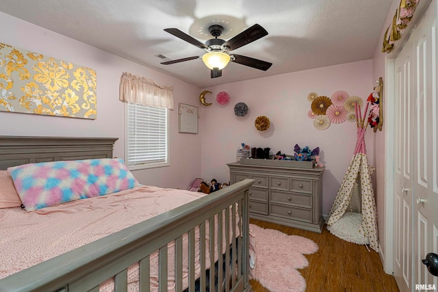 bedroom with a textured ceiling, dark hardwood / wood-style flooring, a closet, and ceiling fan