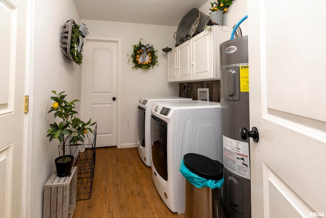 clothes washing area with washer and dryer, light hardwood / wood-style floors, cabinets, and electric water heater