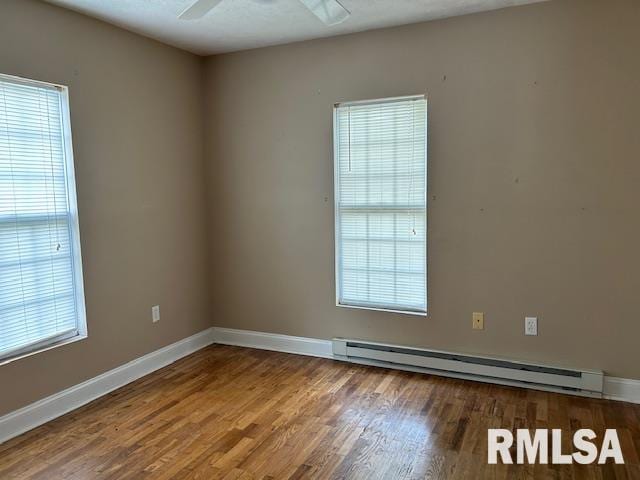 spare room featuring baseboard heating, wood-type flooring, and ceiling fan