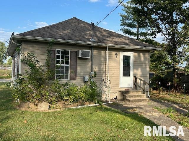 back of property featuring a wall mounted air conditioner and a lawn