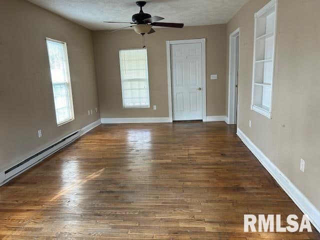 unfurnished room with a textured ceiling, plenty of natural light, and dark hardwood / wood-style flooring