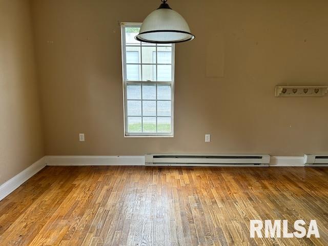 unfurnished room featuring baseboard heating, wood-type flooring, and plenty of natural light