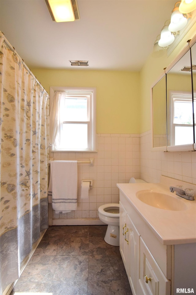 bathroom with vanity, tile walls, and toilet