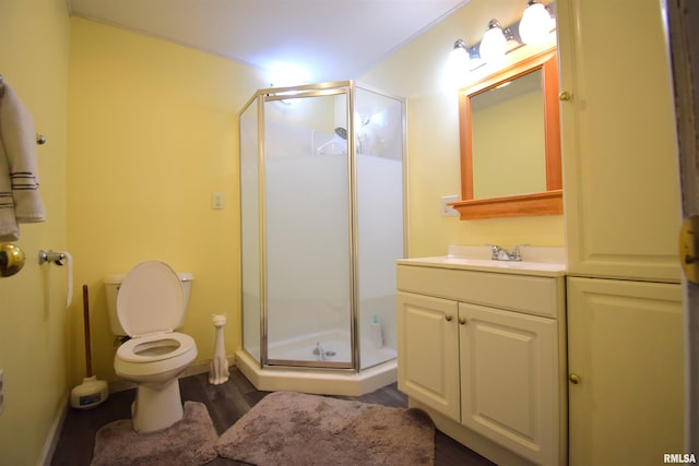 bathroom with hardwood / wood-style flooring, a shower with door, vanity, and toilet