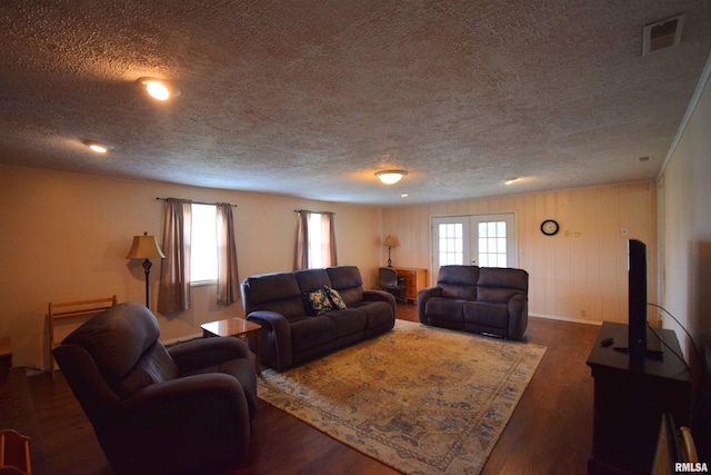 living room with a textured ceiling, dark hardwood / wood-style floors, and french doors