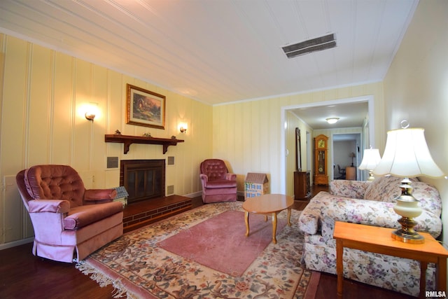 living room with a brick fireplace, dark hardwood / wood-style floors, and crown molding