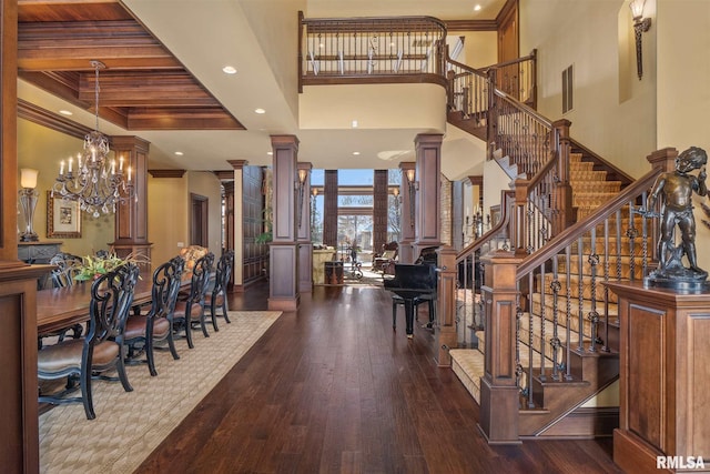 entryway with a towering ceiling, ornate columns, beam ceiling, ornamental molding, and hardwood / wood-style floors