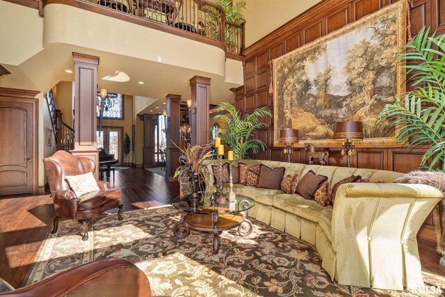 living room featuring a towering ceiling, hardwood / wood-style flooring, and ornate columns