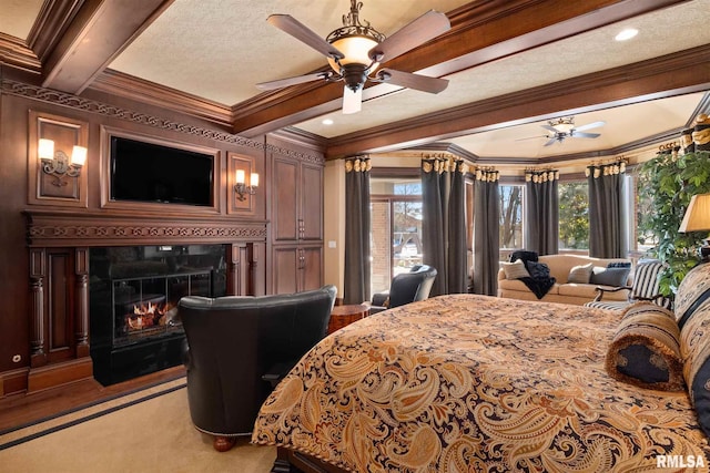 carpeted bedroom with a textured ceiling, beam ceiling, a premium fireplace, ornamental molding, and ceiling fan