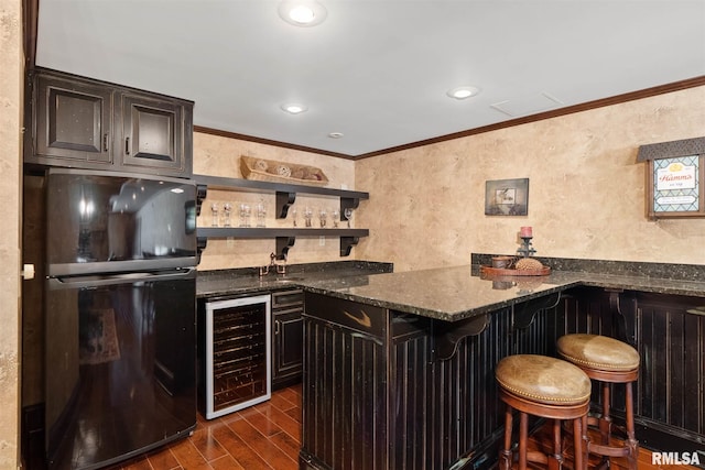 bar featuring dark hardwood / wood-style floors, beverage cooler, ornamental molding, dark stone countertops, and black refrigerator