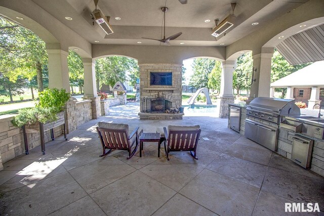 view of patio / terrace featuring ceiling fan, grilling area, an outdoor kitchen, and an outdoor stone fireplace