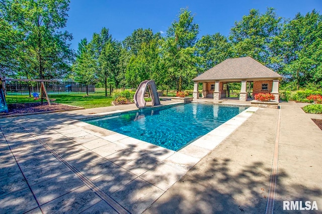 view of pool featuring a yard, a water slide, and a patio area