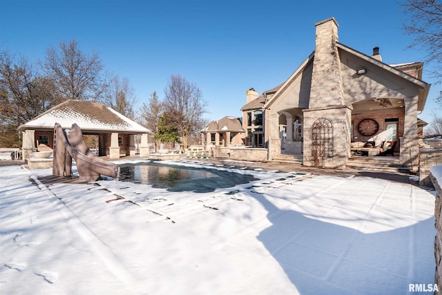 view of pool featuring a patio, a fenced in pool, a water slide, a fireplace, and a gazebo