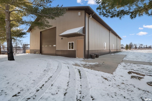 snow covered rear of property with a detached garage