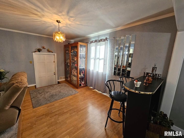 foyer featuring a textured ceiling, crown molding, hardwood / wood-style floors, and a chandelier