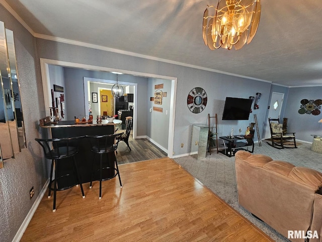 living room featuring wood-type flooring, a notable chandelier, and crown molding