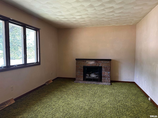 unfurnished living room featuring a textured ceiling, carpet, and a fireplace