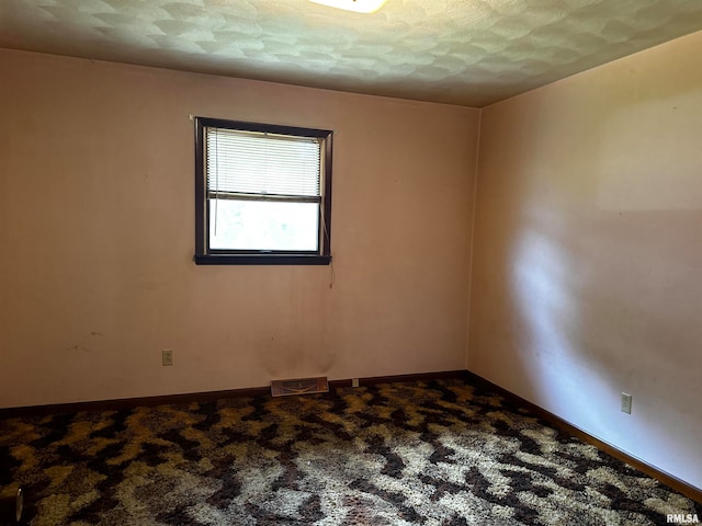 carpeted empty room with a textured ceiling