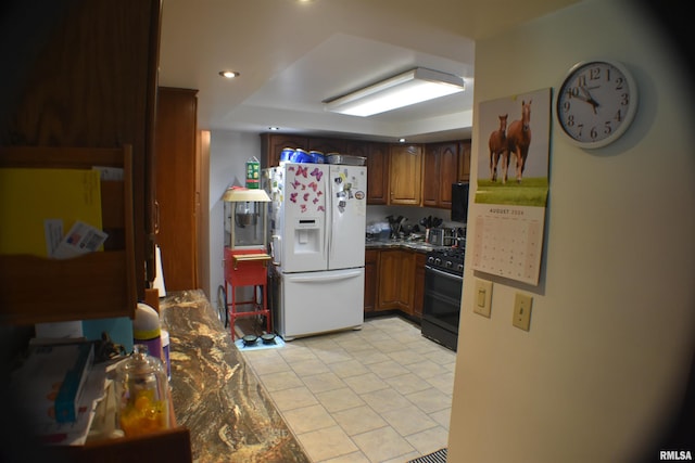 kitchen featuring black gas stove and white refrigerator with ice dispenser