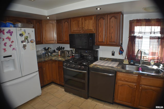 kitchen featuring stainless steel appliances, dark stone countertops, light tile patterned floors, and sink