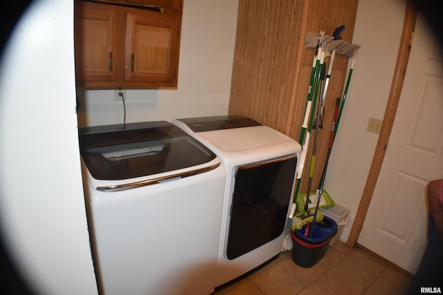 washroom featuring cabinets, washing machine and dryer, and light tile patterned flooring