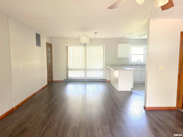 unfurnished living room featuring ceiling fan, dark wood-type flooring, and sink