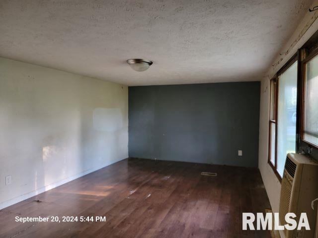 empty room featuring a textured ceiling and dark wood-type flooring