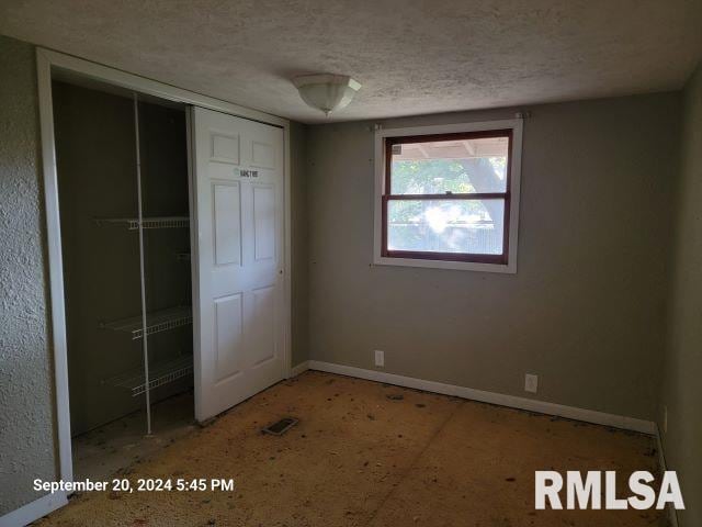 unfurnished bedroom featuring a textured ceiling and a closet