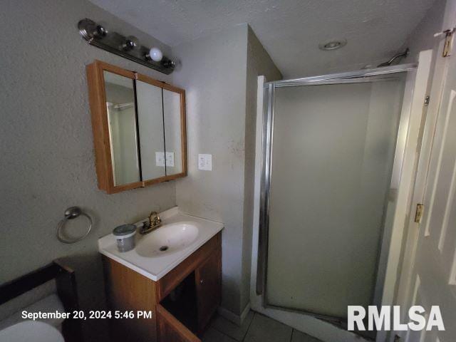 bathroom with tile patterned flooring, vanity, and a shower with shower door