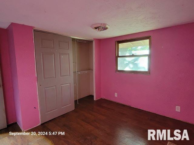 unfurnished bedroom featuring a closet and dark wood-type flooring