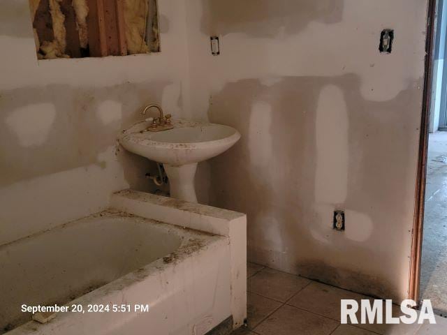 bathroom with tile patterned flooring and a tub