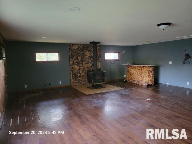 unfurnished living room featuring hardwood / wood-style flooring, a wood stove, and a wealth of natural light