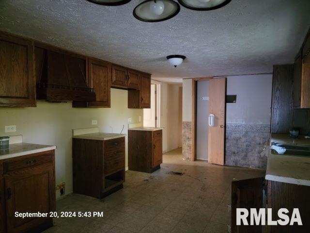 kitchen featuring sink, custom range hood, and a textured ceiling