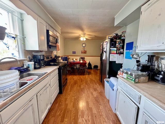 kitchen featuring light hardwood / wood-style floors, white cabinetry, stainless steel appliances, backsplash, and ceiling fan