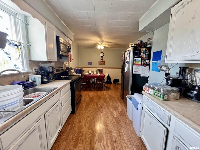 1106 N 11th St, Murphysboro, IL 62966 - kitchen featuring white cabinetry, light countertops, stainless steel appliances, light wood finished floors, and ceiling fan