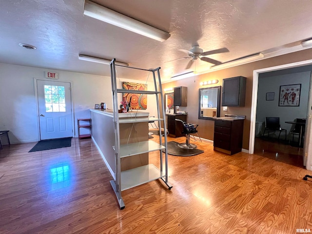 kitchen featuring dark brown cabinets, light wood-type flooring, ceiling fan, and a textured ceiling