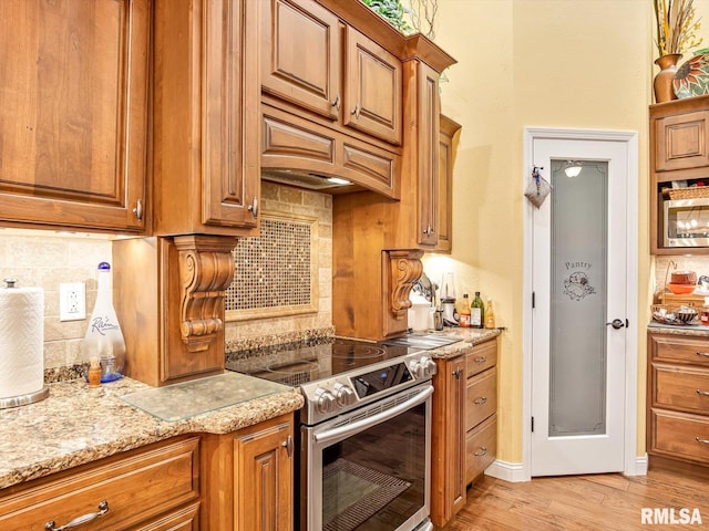 kitchen featuring appliances with stainless steel finishes, backsplash, light hardwood / wood-style floors, and light stone counters