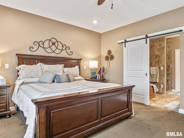 bedroom featuring ensuite bath, ceiling fan, light colored carpet, and a barn door